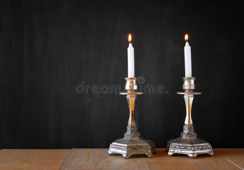 Dos candelabros incendio velas a través de de madera mesa a pizarra.