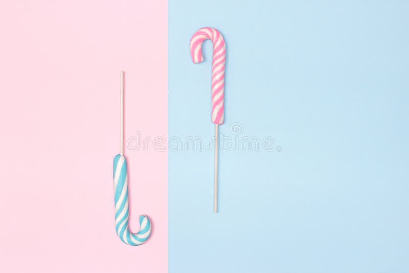 Two candy canes on pastel blue and pink background. Minimalistic composition with copy space. Holiday concept