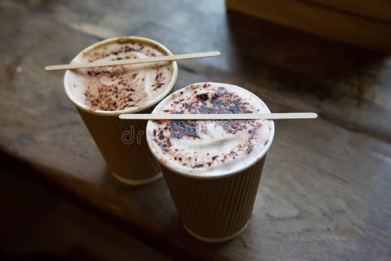 Two cappuccinos in paper cups