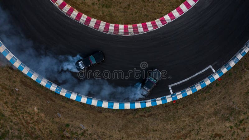 Two cars drifting battle on race track with smoke, Aerial view two car drifting battle