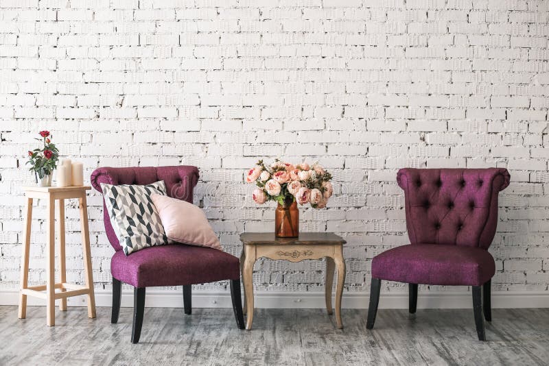 Two chairs and a table with bouquet of  flowers in a vase near white brick wall vintage style