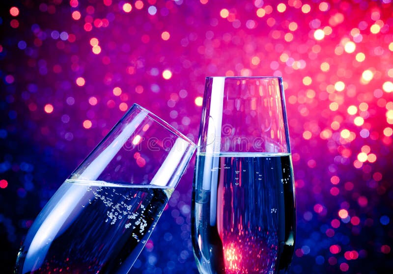 Two champagne flutes with gold bubbles on blue tint light bokeh background stock photo Two champagne flutes with gold bubbles on blue tint light bokeh background stock photo