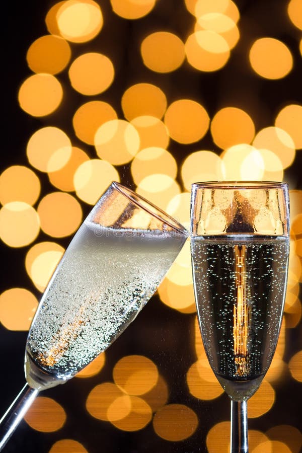 Two Champagne Glasses with Bubbles and Bokeh Lights in the Back Stock
