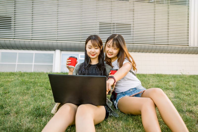 https://thumbs.dreamstime.com/b/two-charming-joyful-young-asian-girlfriends-having-fun-sitting-green-grass-outdoors-city-looking-laptop-182051209.jpg