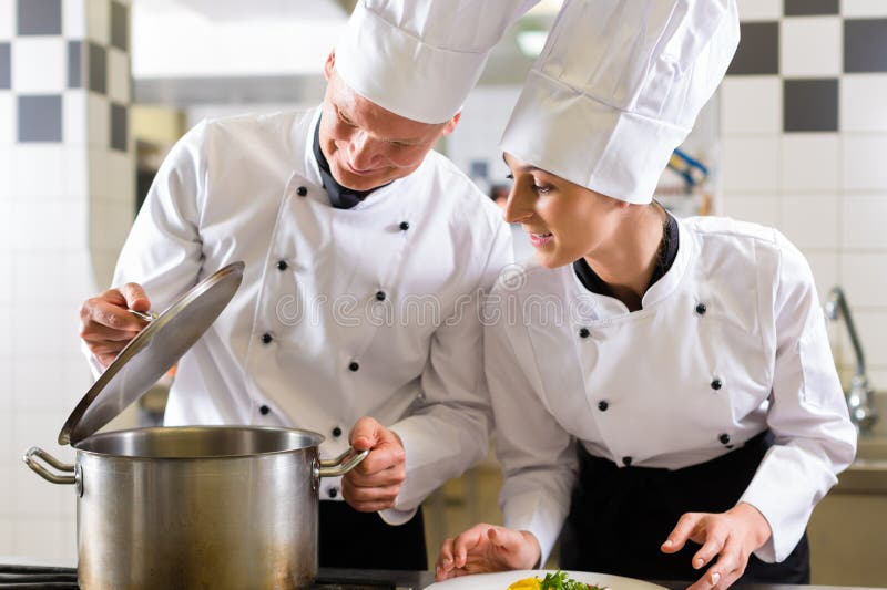 Two chefs in team in hotel or restaurant kitchen royalty free stock photography