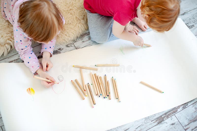 Children Draw with Pencils Lying Down and Sitting on the Floor Stock