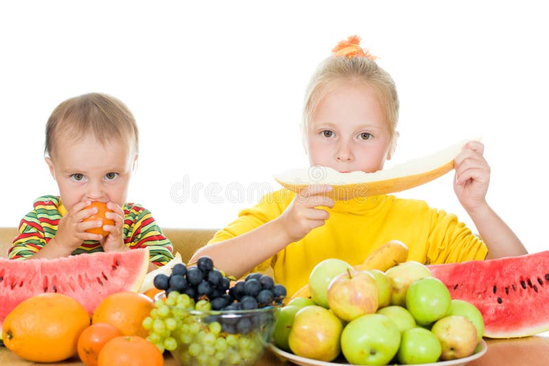 Two children eat fruit at a table