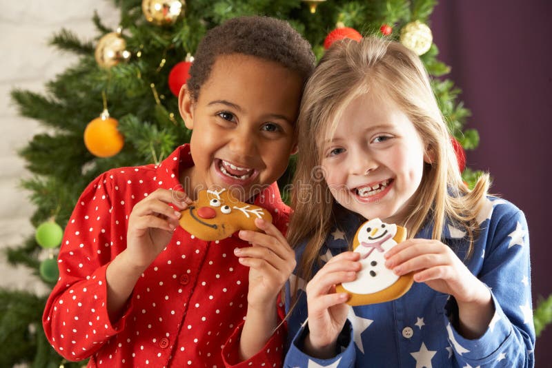 Two Children Eating Treats In Front Of Tree