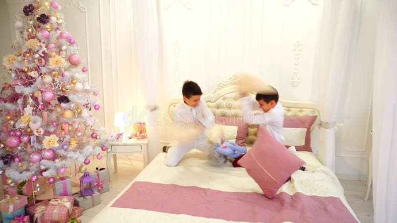 Two Children of Gay Child of Twin Brother are Having Fun and Fighting with Pillows on Bed in Bright Room with Christmas Stock Footage - Video of caucasian, blanket: 97350204