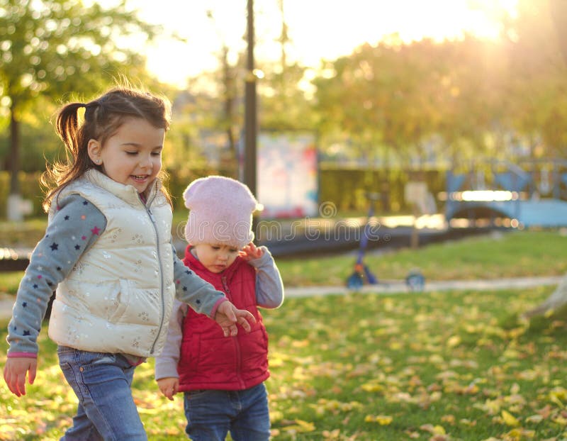 Two children hugging on autumn walk in the park outdoors after playing with fallen leaves in the rays of sunset stock images Two children hugging on autumn walk in the park outdoors after playing with fallen leaves in the rays of sunset stock images
