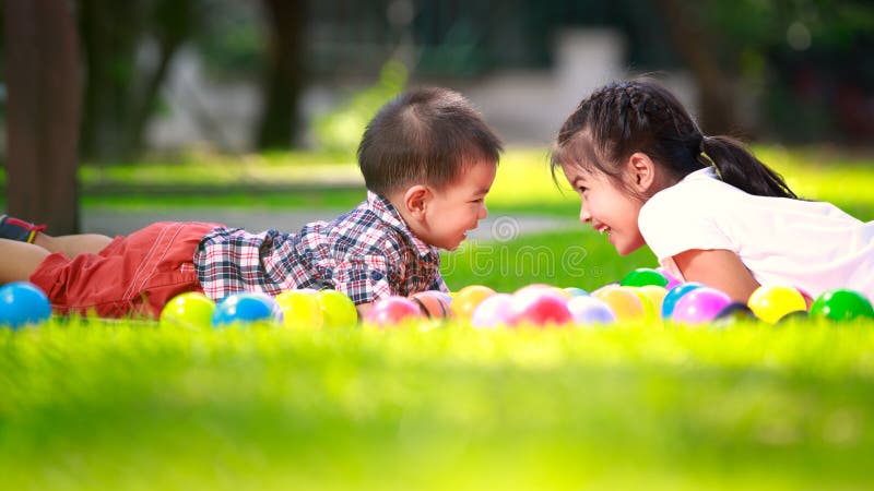 Two children are laying on green grass and smile