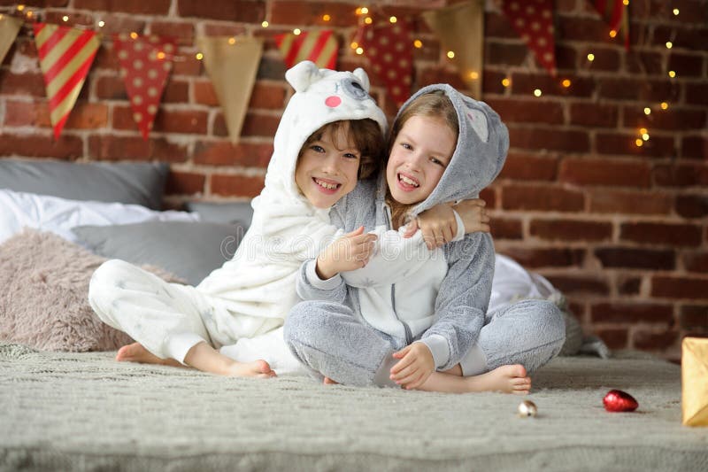 Two Children in Pajamas Sitting on the Bed Waiting for Christmas Gifts ...