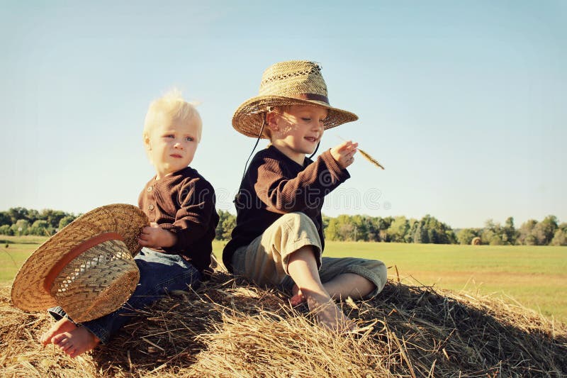 Two Children Sitting on Hay Bale in Autumn