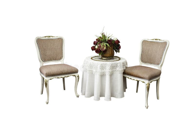 Two classic chairs next to a round coffee table with white embroidery cloth and a brass pot filled with roses