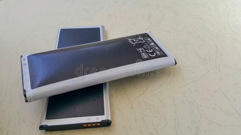 Two close-up batteries, one regular and the other a swollen lithium-ion smartphone battery. A damaged battery is ready to burn or royalty free stock photography