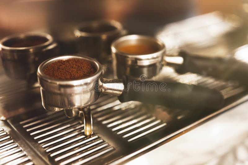 Two coffee holders one with ground coffee near professional coffee machine close up, barista tools