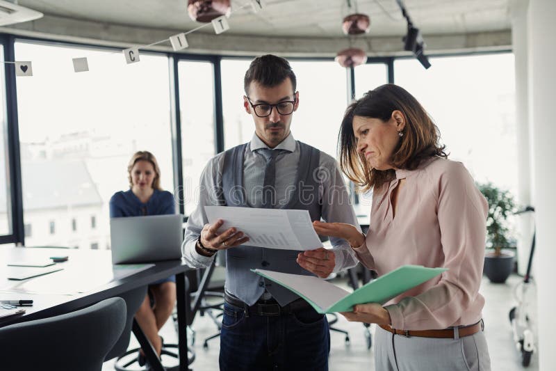 Two collegues talking about project document, standing in modern office. royalty free stock photos