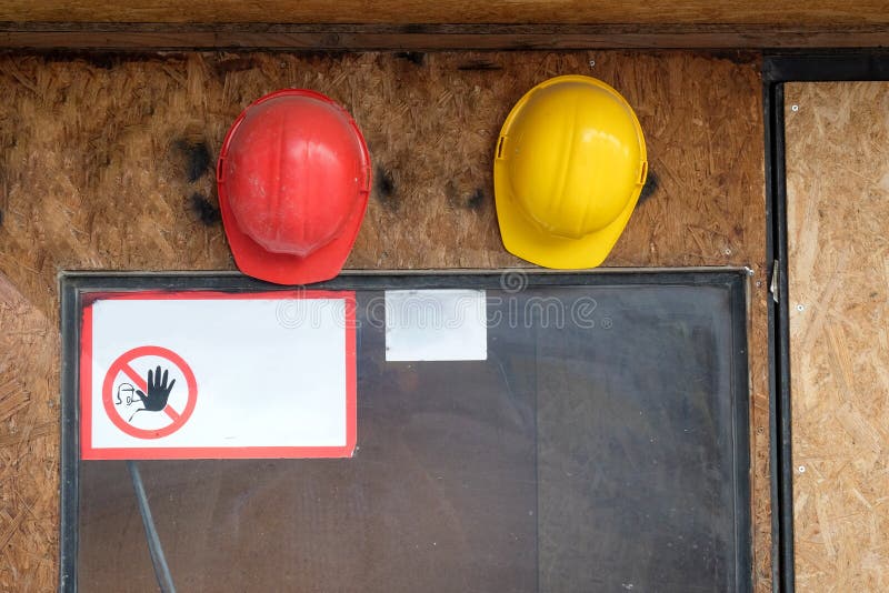 Two construction hard hats on the wall with warning sign royalty free stock images Two construction hard hats on the wall with warning sign royalty free stock images