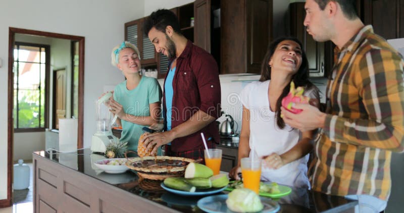 Two Couples In Kitchen Cooking Together, Young Woman And Man Group Talking Cut Vegetables And Fruits Prepare Healthy