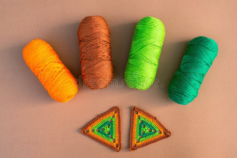 Two Crochet Motifs in Green and Orange Tones, Four Skeins of Yarn, Crochet  Hook and Small Scissors on Beige Backgr…