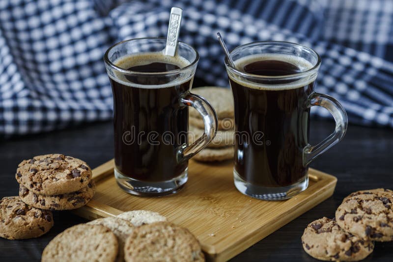 Dve poháre z káva a čokoláda a ovsená kaša sušienky na tmavý drevený.
