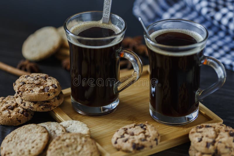 Dve poháre z káva a čokoláda a ovsená kaša sušienky na tmavý drevený.