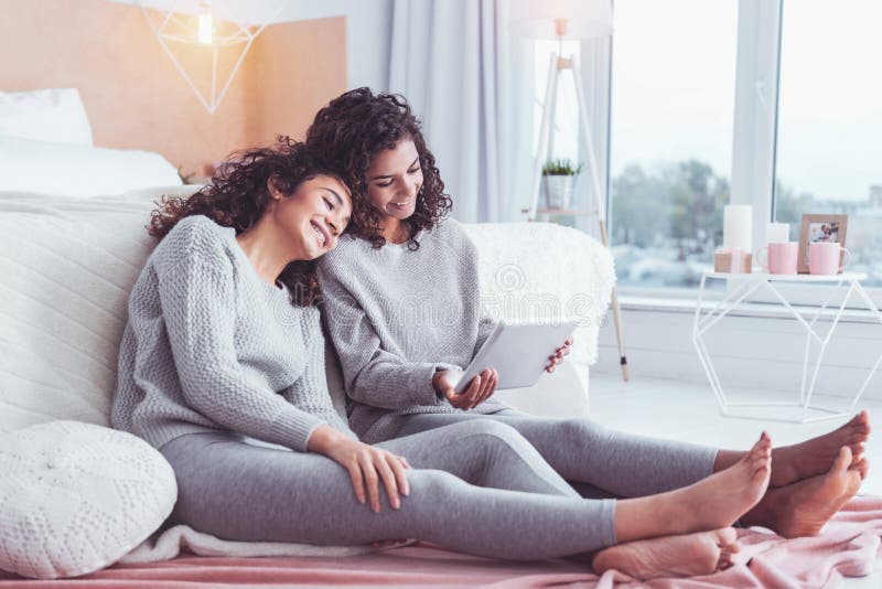 Two curly-haired sisters feeling rested watching movie stock photo