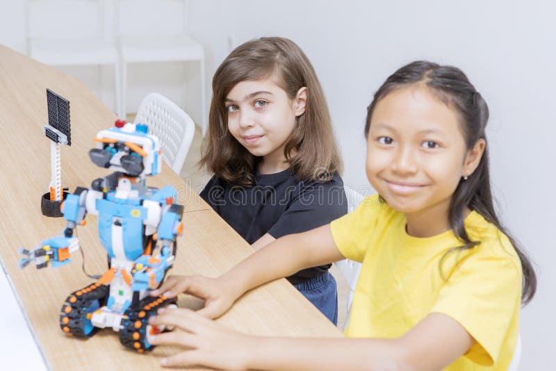 Two cute girls constructing a Lego robot in class stock photo