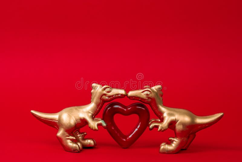 Two  cute golden dinosaurs with red heart on a red background. Creative minimal greeting card on Valentines day. Love concept