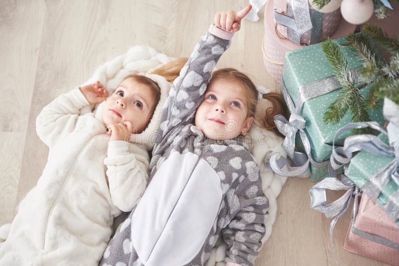 Two cute little girl in pajamas lying under Christmas tree among presents royalty free stock photos Two cute little girl in pajamas lying under Christmas tree among presents royalty free stock photos