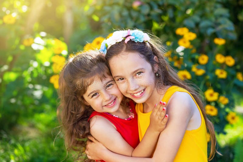 Two cute little girls embracing and smiling at the sunny country