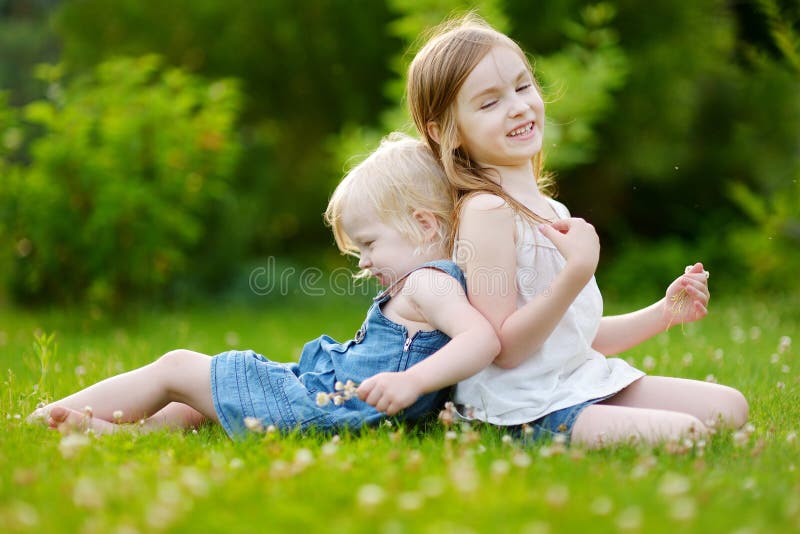 Two Cute Little Sisters Sitting on the Grass Stock Photo - Image of ...