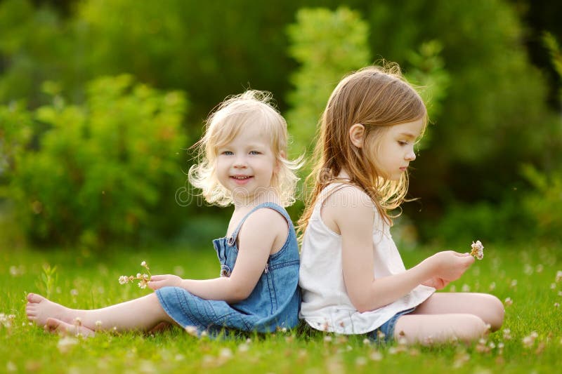 Two Cute Little Sisters Sitting on the Grass Stock Photo - Image of ...