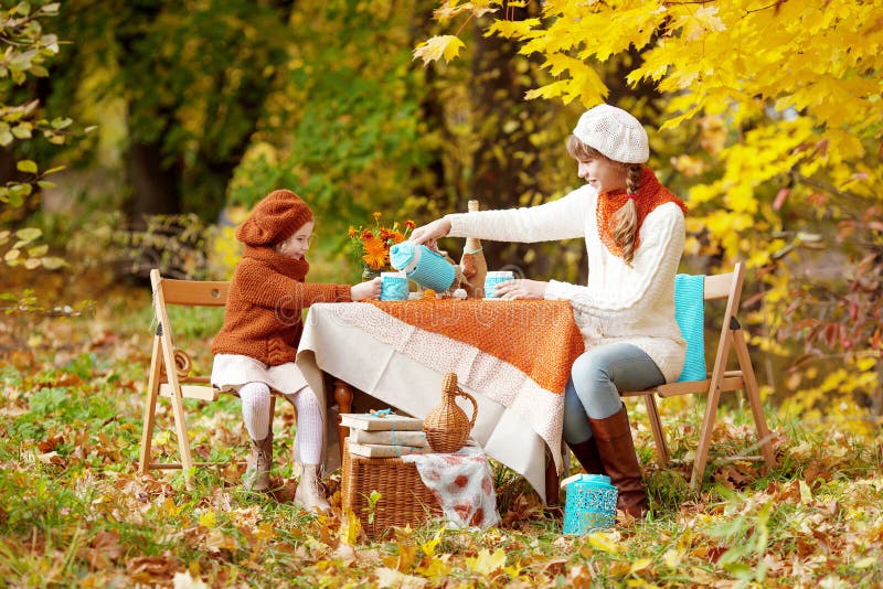 Two cute sisters  on picnic in autumn park. Adorable little girls  having tea party outside in the autumn garden.  Girls drinking