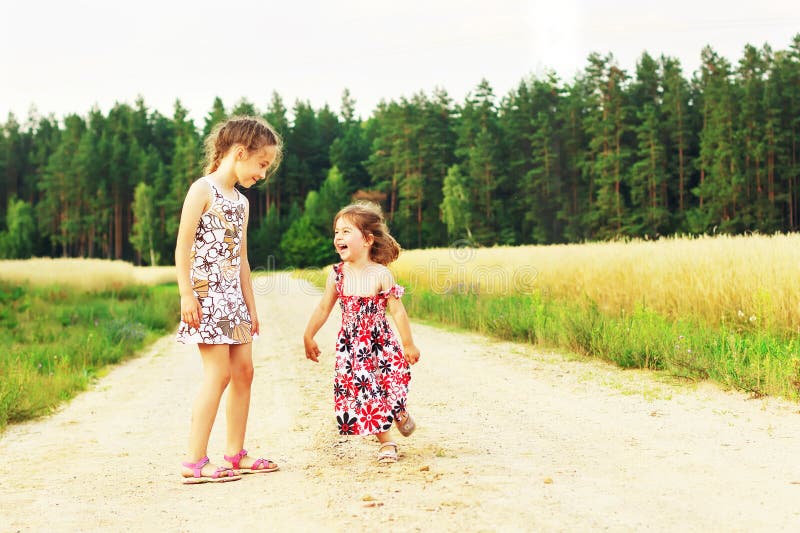 Two Cute sisters running on a green grassy field with smiles on their faces. Kids spending time together outdoor. stock images Two Cute sisters running on a green grassy field with smiles on their faces. Kids spending time together outdoor. stock images