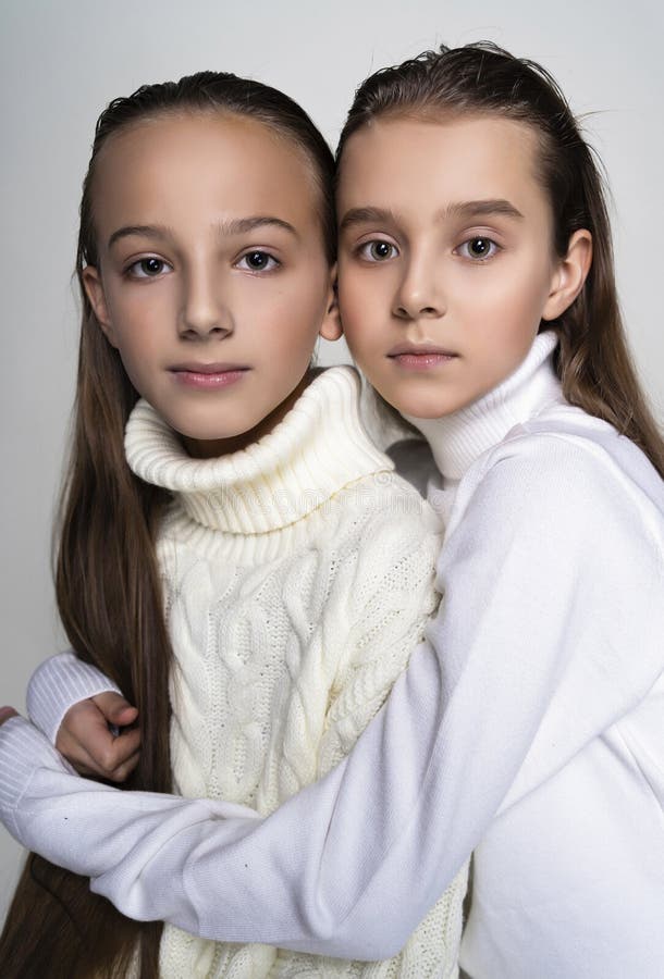 Two cute teenage girlfriends schoolgirls wearing white turtleneck sweaters, sit, hugging each other in a friendly way. on stock photography Two cute teenage girlfriends schoolgirls wearing white turtleneck sweaters, sit, hugging each other in a friendly way. on stock photography