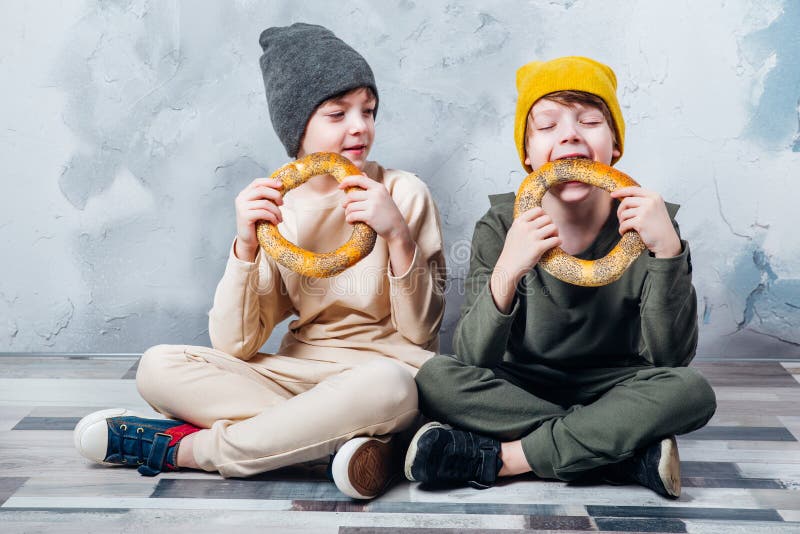 Two cute twin boys sitting on floor and happily eating bagel royalty free stock photo Two cute twin boys sitting on floor and happily eating bagel royalty free stock photo