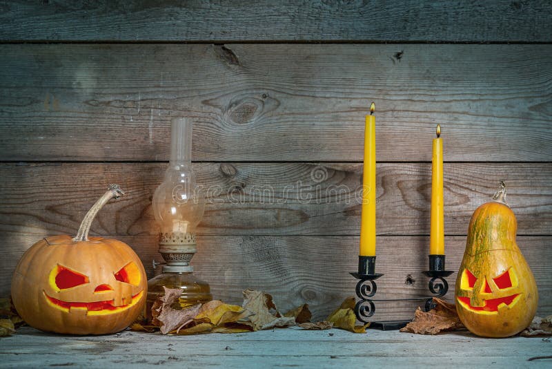 Couple of decorated pumpkins for a Halloween on a mystical autumn background with candles and gas lamp