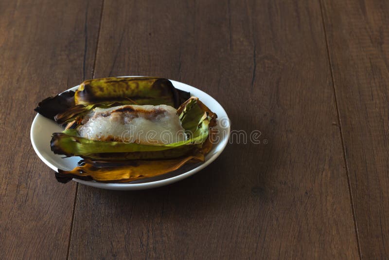 https://thumbs.dreamstime.com/b/two-delicious-grilled-sticky-rice-wrapped-banana-leaves-plate-filled-taro-wooden-background-118047919.jpg
