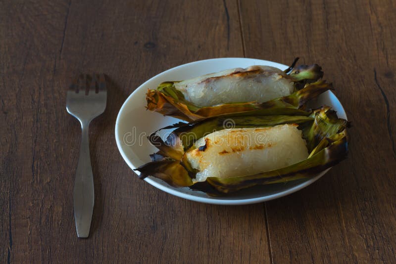 https://thumbs.dreamstime.com/b/two-delicious-grilled-sticky-rice-wrapped-banana-leaves-plate-filled-taro-wooden-background-118047931.jpg