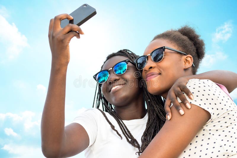 Two diverse african girls taking self portrait with phone.