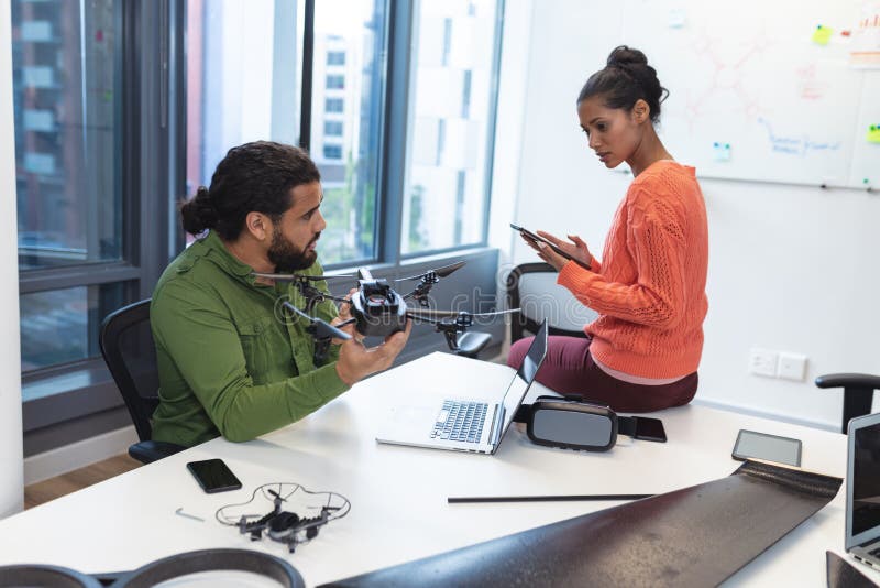 Two diverse creative colleagues sitting at desk talking royalty free stock images