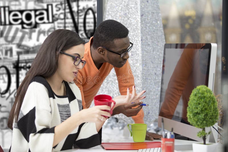Two diverse work colleagues smiling and writing down notes while sitting together at a table in a modern office stock photos