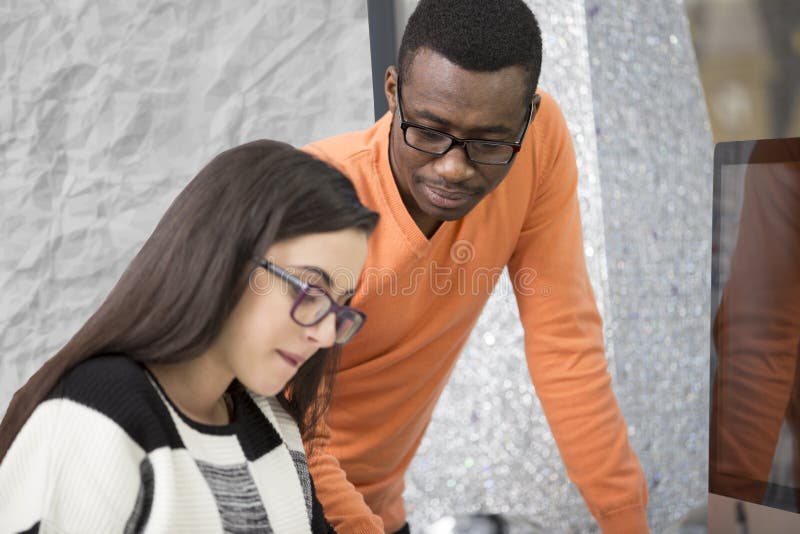 Two diverse work colleagues smiling and writing down notes while sitting together at a table in a modern office royalty free stock image
