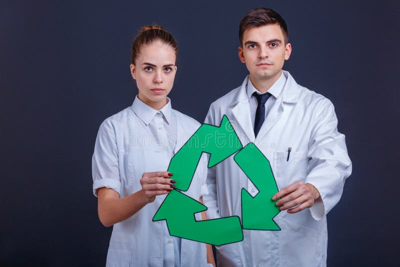 Two doctors in white uniform, a guy and a girl, stand and hold a sign, three rotating green arrows. stock photography Two doctors in white uniform, a guy and a girl, stand and hold a sign, three rotating green arrows. stock photography