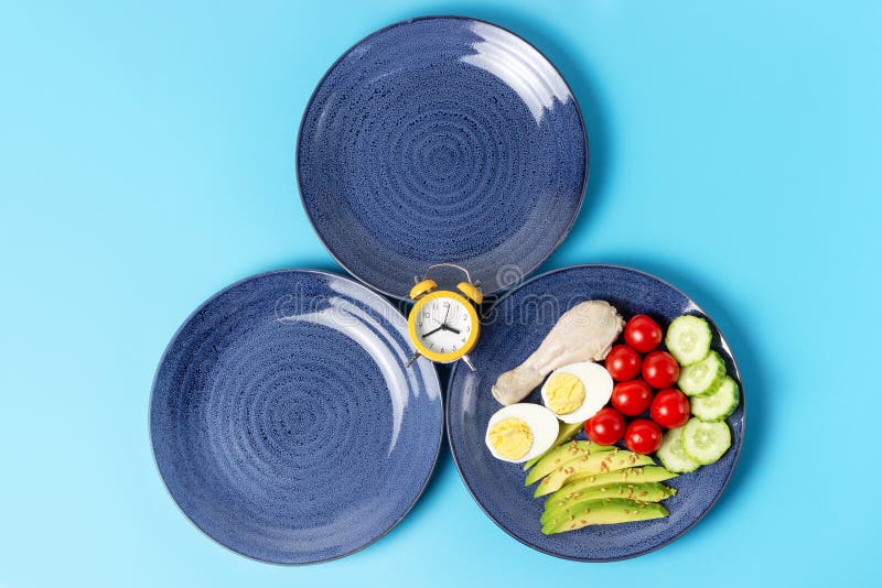 Two empty plates and plate with food on blue background royalty free stock image