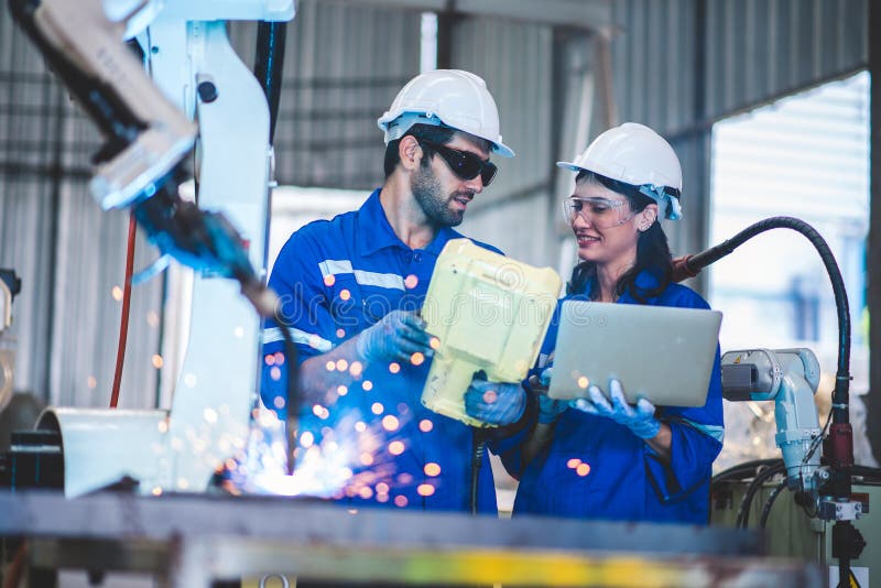 Two engineers mechanic using computer controller Robotic arm for welding steel in steel factory workshop. Industry robot royalty free stock images