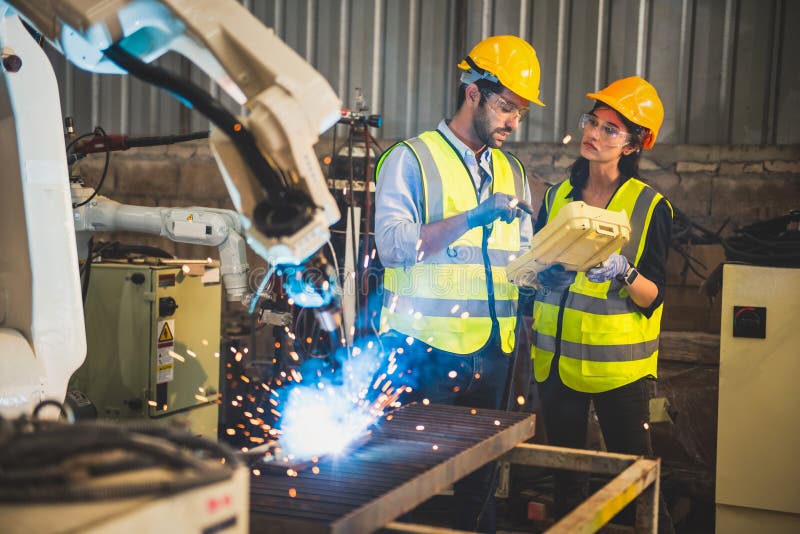 Two engineers mechanic using computer controller Robotic arm for welding steel in steel factory workshop. Industry robot stock images