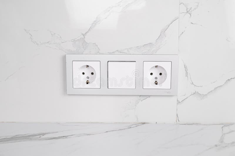 Two European Style Sockets and Light Switch on Marble Wall. Placement