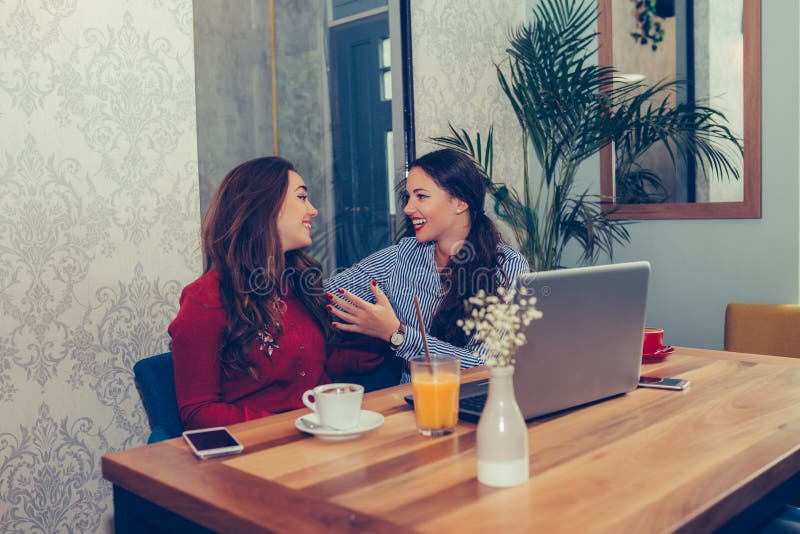 Two excited women reading online good news on a laptop while sitting in cafe stock photos Two excited women reading online good news on a laptop while sitting in cafe stock photos